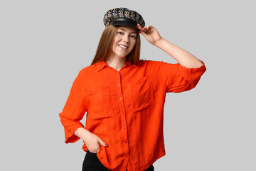 Wall Mural - Stylish young girl in hat and shirt on light background