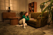 © Pixel-Shot - Young woman using laptop on sofa at home in evening