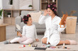 © Pixel-Shot - Little Asian girl and her mother with hair curlers doing makeup at home