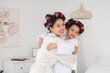 © Pixel-Shot - Cute little Asian girl and her mother with hair curlers hugging in bedroom