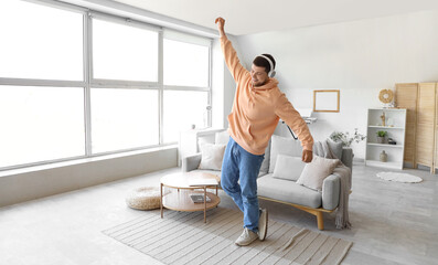 Wall Mural - Young bearded man in headphones dancing at home