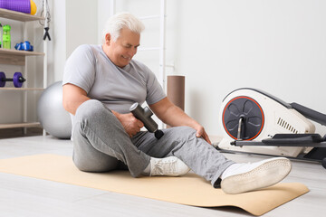 Sticker - Sporty mature man massaging his leg with percussive massager in gym