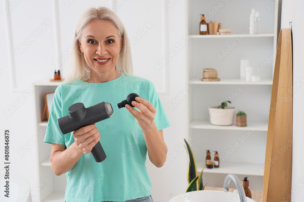 Mature woman with percussive massager in bathroom