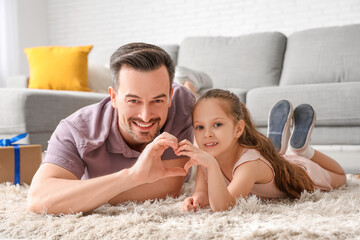 Sticker - Father and his little daughter lying on floor and making heart with their hands in room. Father's Day celebration