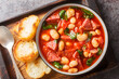 Spanish stew of butter beans, chorizo and spinach in tomato sauce close-up in a bowl on the table. Horizontal top view from above
