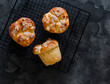 Homemade brioche buns with almond petals on a baking rack on a dark background, top view