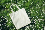 Fototapeta  - Mockup of a white tote bag laying on grass, White cotton or mesh eco bag on green grass