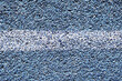 White line sports track background. Paint on blue grain. Articial basketball field closeup line. Asphalt bitumen texture.