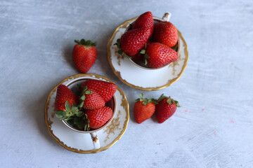 Sticker - Strawberries in porcelain cups on a white background. Light grey textured background with space for text. Ripe summer berries close up photo. Healthy eating concept. 