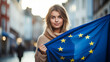 Young woman with the flag of the European Union against the background of city streets