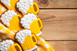 Delicious gingerbread cookies shaped like beer mugs, decorated with icing, displayed on a wooden table with a yellow and white checkered cloth