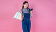Portrait happy beautiful shopaholic asian woman carry shopping bags, winter fashion sale model Asia girl with mobile phone, outlet department store advertise concept isolated pink banner background