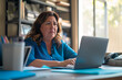 © GustavsMD - Concentrated Businesswoman Working at Desk. Mature woman in blue blouse focused on her work on a laptop in a well-lit office surrounded by books.
