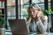 © GustavsMD - Mature Businesswoman Feeling Stressed at Work. Exhausted mature businesswoman experiencing stress while working on a laptop in a modern office environment.