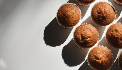 Wall Mural - Freshly baked bran muffins on white table. Tasty food for breakfast. Delicious baked goods. Top view