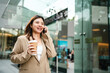 Business entrepreneur asian woman drink coffee use smartphone outside city office building