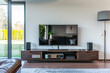 Minimal view of a living room with a dark wooden TV console and a big screen.