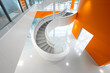 Spiral staircase top view leading to a white-floored entryway with an orange wall.