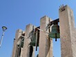 Outdoor three massive church bells on concrete columns in front of catholic Church of Our Lady Of The Rosary in Razanac, northern Dalmatia, Croatia, sunlit by august summer sunshine.