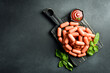 Boiled meat sausages, ready to eat. Top view. On a black stone background. Rustic style.