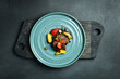 Baked goose liver with caramelized apple and strawberries. On a black stone background. In a plate, close-up.