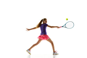 Sportive young girl, tennis athlete in comfortable vibrant uniform playing tennis in motion against white studio background. Concept of professional sport, movement, tournament, action. Ad