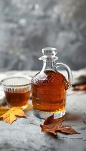 Bottle And Glass Of Tasty Maple Syrup On Grey Background