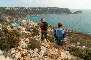 Wall Mural - Unrecognizables hikers in a row, walking on the rocks, the sea is on the background.