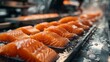 A conveyor belt with a row of salmon fillets on it