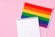 Blank mock up notebook on rainbow LGBTQ flag, pink background. June proud pride month parade, gay marriage, coming out day concept, human rights, tolerance. Flat lay, top view place for text or logo