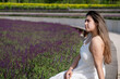 pretty young woman in white dress sitting at the sage flower field.