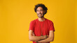 An attractive man with curly hair, dressed in red T-shirt,  listens and disagrees while looking at camera isolated on yellow background in studio