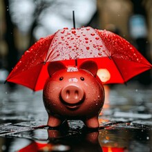 A Red Piggy Bank Sits In The Rain With A Red Umbrella.