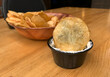 A bowl of freshly made potato chips and a small black bowl with a dip