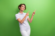© deagreez - Photo of young woman student work as courier directing fingers mockup recommend hour payment first job isolated on green color background