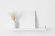 White canvas mockup with a pampas decoration on the wall shelf.