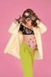 emotional pregnant woman in bright pin-up clothes on pink background, belly with flower pattern