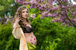 young girl pregnant near trees with cherry blossoms, belly with flower ornament, spring vibe