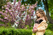 curly young girl pregnant near trees cherry blossoms, belly with flower, dreamy, in a sense of peace