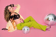 pregnant young girl sitting on a pink background with a disco ball, bright clothes and lingerie in pin up style