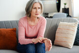 Fototapeta  - Sad senior woman touching hand, measuring blood pressure, sitting on comfortable sofa