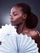 Fashion, thinking and black woman with origami fans in studio, beauty and dark background. Thought, female person or model with traditional craft paper or art for elegant, and creative design