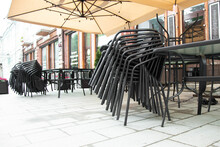 Closed Outdoor Cafe . Stacked Chairs Near Cafe Tables Standing On Street
