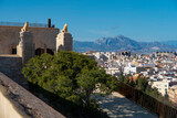Fototapeta  - Lions looking at San Fernando's Castle (Castell de Sant Ferran) creating impregnable defensive walls (fortresses). In the background, the mountains surrounding the city of Alicante (Costa Blanca),