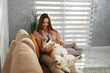 The intimate scene captures the comfort of a pet owner bonding with her fluffy,Pembroke Welsh Corgi in a warm indoor setting