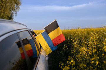 flags of Ukraine and Germany hang from the car window against of a blooming rapeseed field and sky. The concept of cooperation and partnership between two European countries. Support for Ukraine