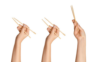 Wall Mural - A set of female hands holding wooden chopsticks for sushi or rolls on a blank background.