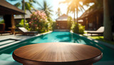 Fototapeta  - Empty round wood table with a luxurious tropical pool in the background.