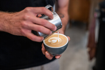 Close-up of a coffee cup in the hands of the barista. Morning coffee.