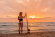 Surfgirl with blonde hair go to surfing. Woman holding surfboard on a beach at sunset or sunrise. Surfer and ocean